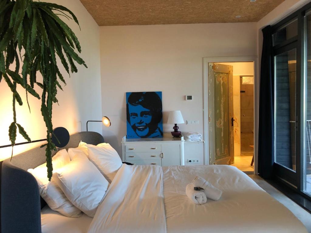 een slaapkamer met een wit bed met een plant bij B and Be Happy Friesland in Lioessens