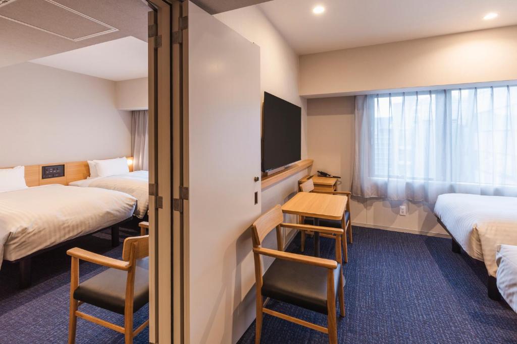 um quarto de hotel com duas camas e uma televisão em Sotetsu Fresa Inn Kyoto-Kiyomizu Gojo em Quioto