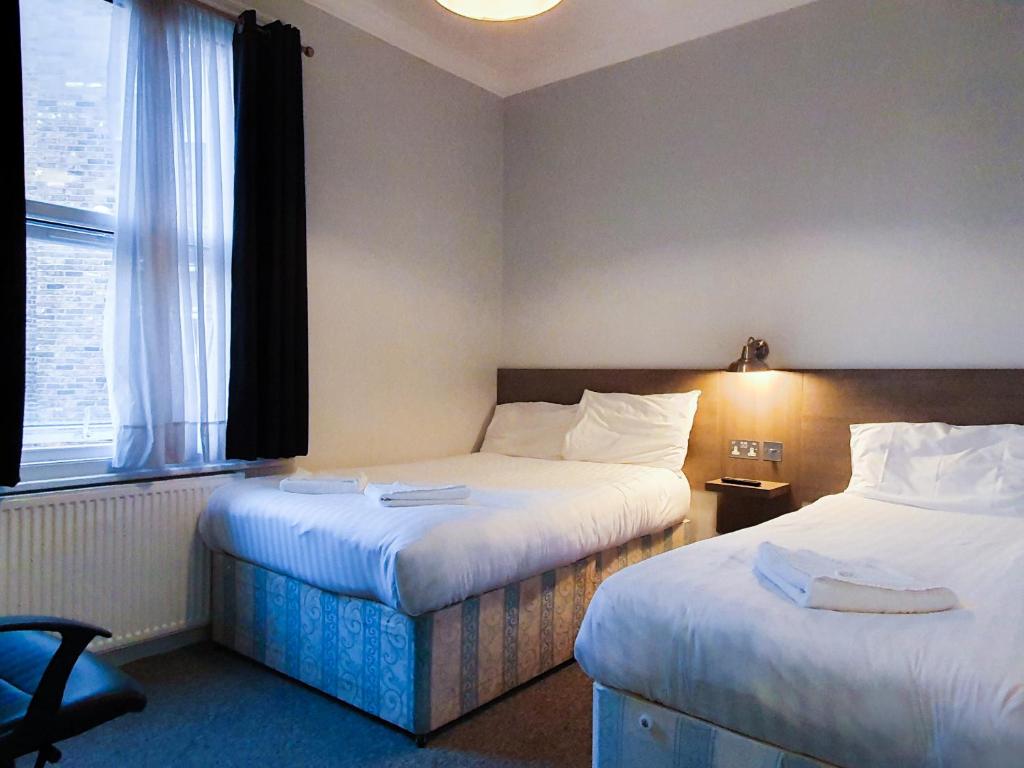 Habitación de hotel con 2 camas y ventana en Plaza Hotel en Londres