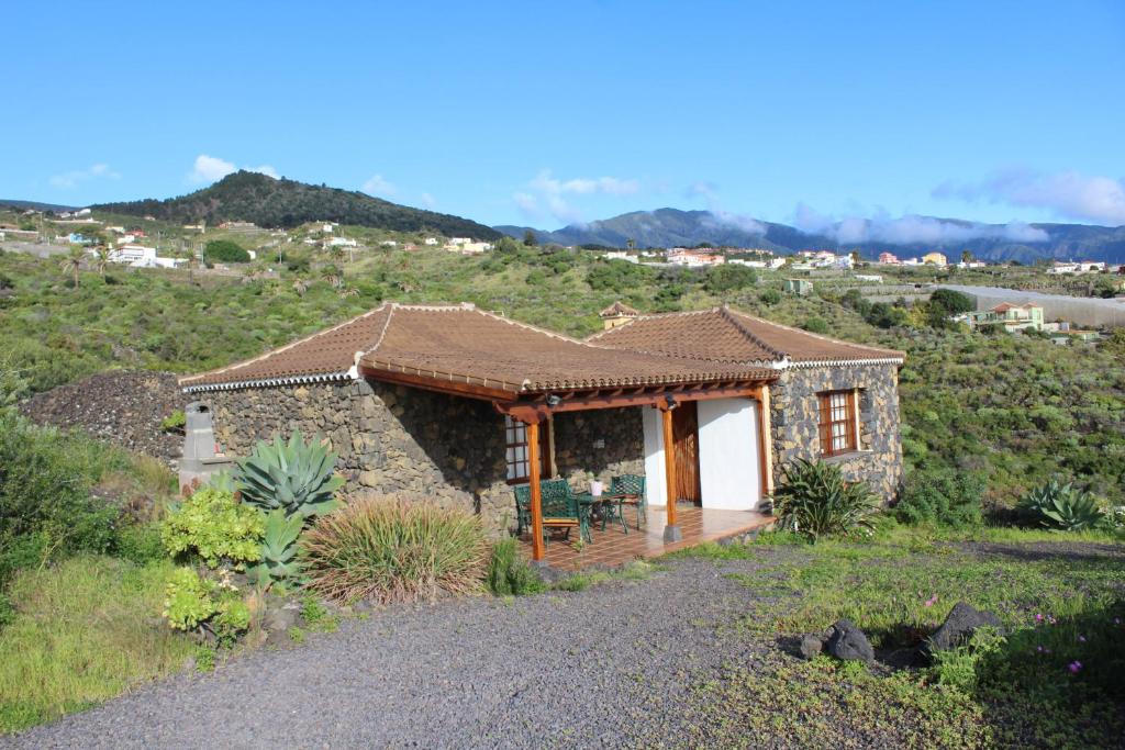 una pequeña casa de piedra con porche en una colina en Casa Las Caracolas en Mazo