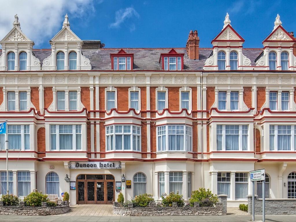 a large red and white building on a street at Dunoon Hotel in Llandudno