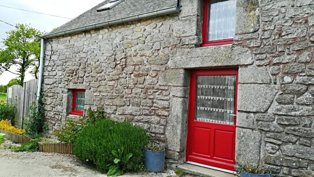 - un bâtiment en pierre avec une porte rouge et des fenêtres dans l'établissement Maison de 2 chambres avec jardin amenage et wifi a Questembert, à Questembert
