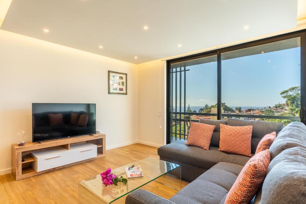 uma sala de estar com um sofá e uma televisão em Magnolia Apartment by Atlantic Holiday no Funchal