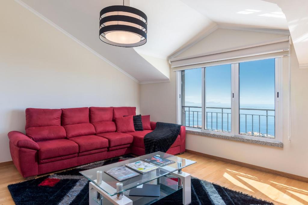 a living room with a red couch and a large window at Savana Apartment By Atlantic Holiday in Caniço