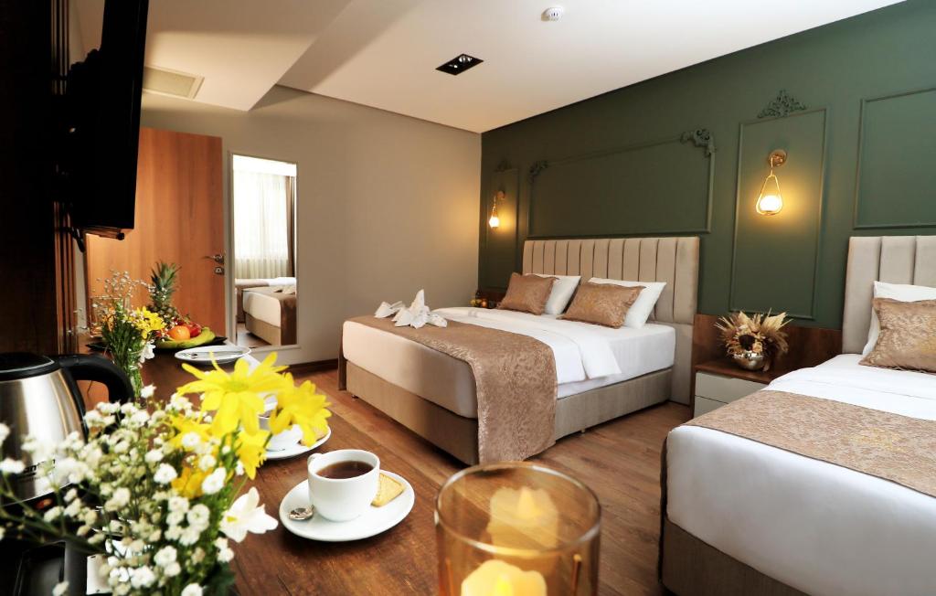 a hotel room with two beds and a table with flowers at Bayrak Grand Hotel in Trabzon