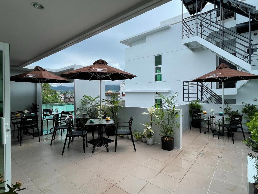 patio ze stołami, krzesłami i parasolami w obiekcie J Spazio Apartelle and Cafe w mieście Baranghauon