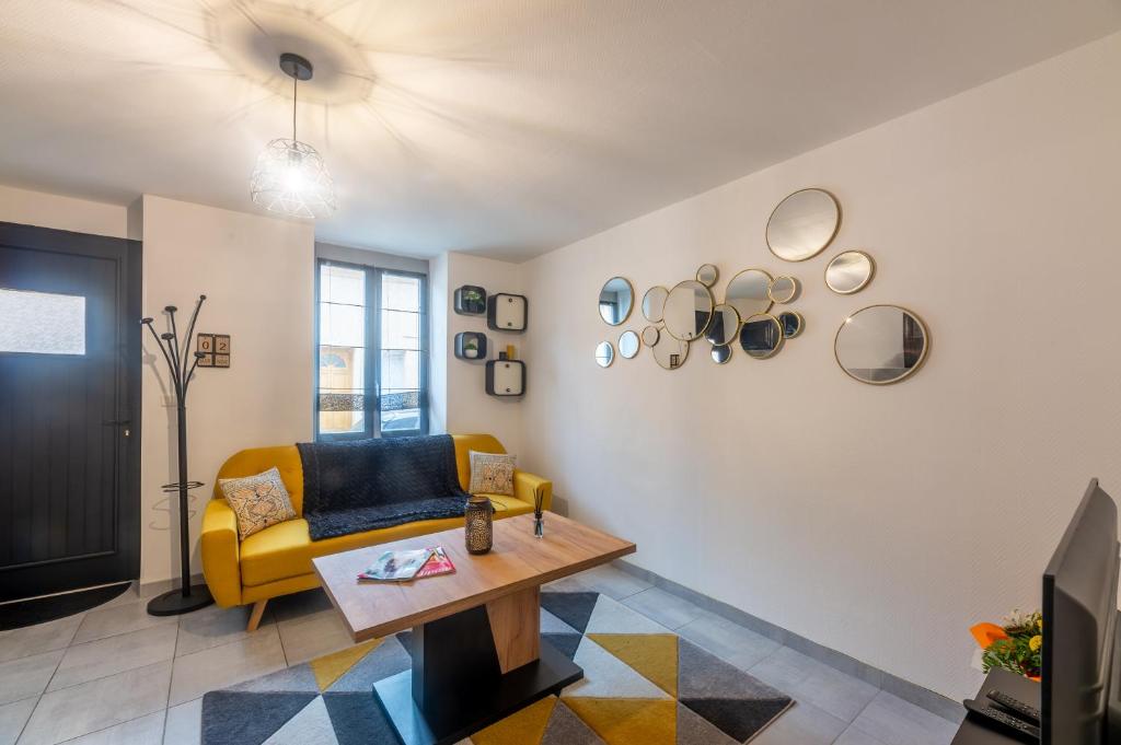a living room with a yellow couch and a table at CHOUETTISSIME Topséjour-Roanne 1 chambre All Inclusive in Roanne