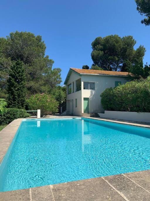une grande piscine bleue devant une maison dans l'établissement VIlla Saint Clair avec piscine, à Sète