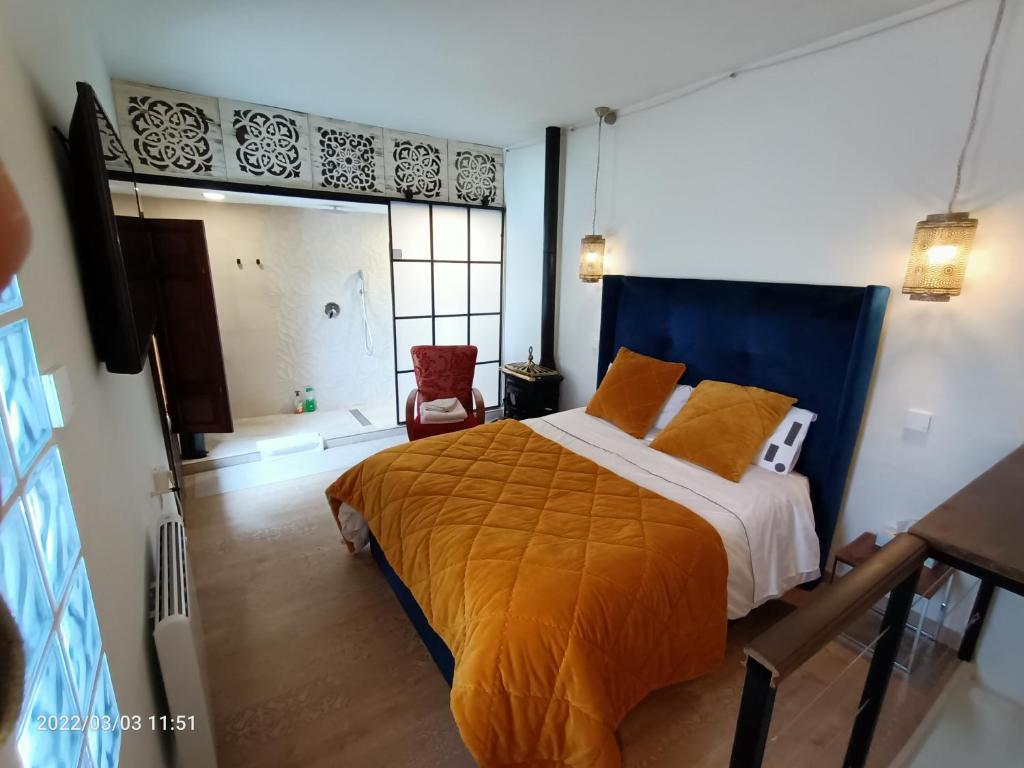 een slaapkamer met een groot bed en een oranje deken bij Casa de Adonay 3 in Huétor Vega