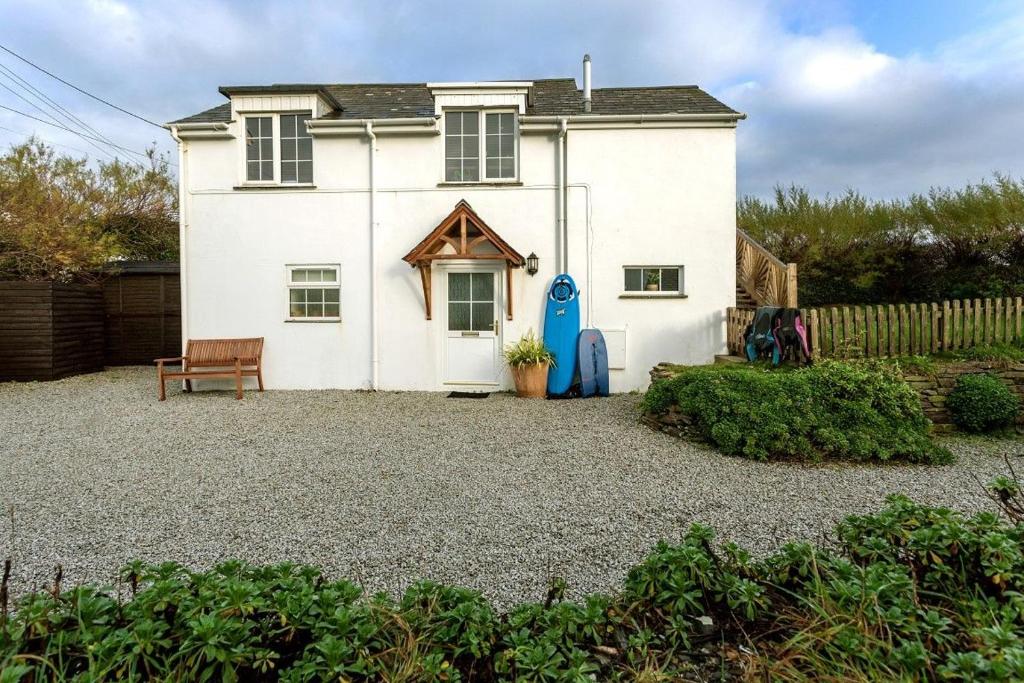 een wit huis met een bankje ervoor bij Arnold Cottage in Saint Merryn