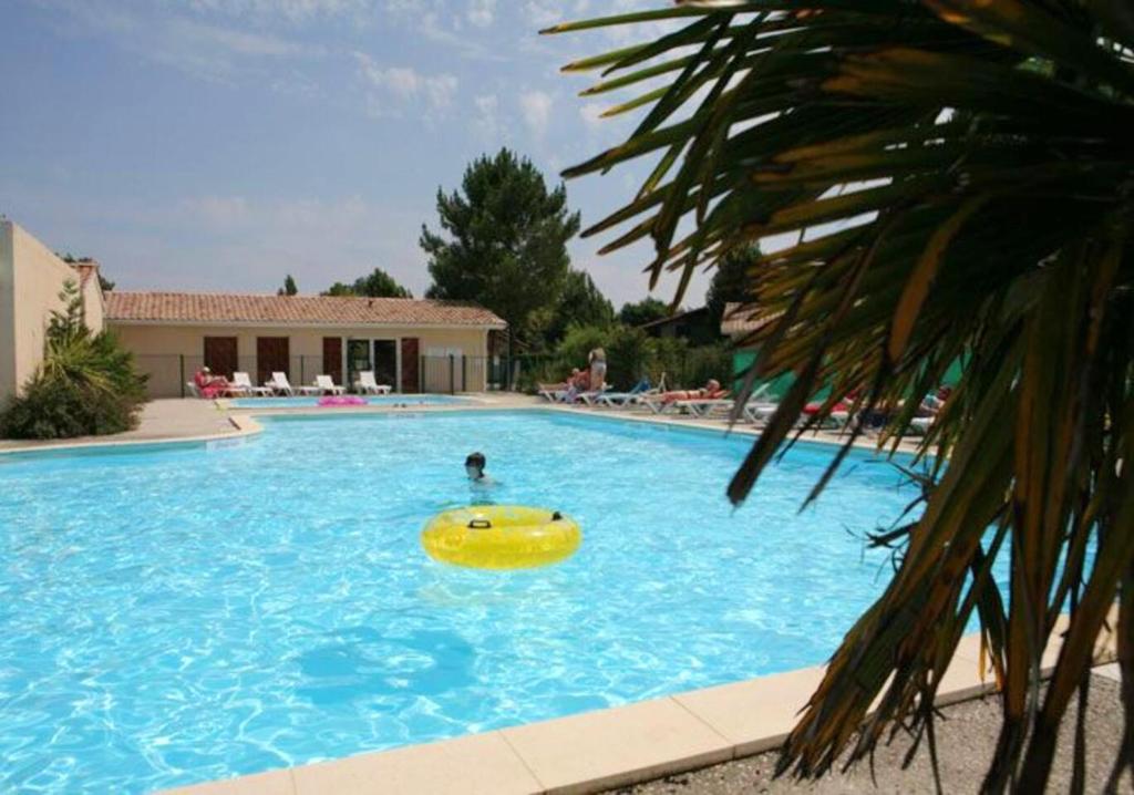 eine Person in einem großen Pool mit gelbem Frisbee in der Unterkunft Maison d'une chambre avec vue sur le lac piscine partagee et jardin amenage a Hourtin in Hourtin