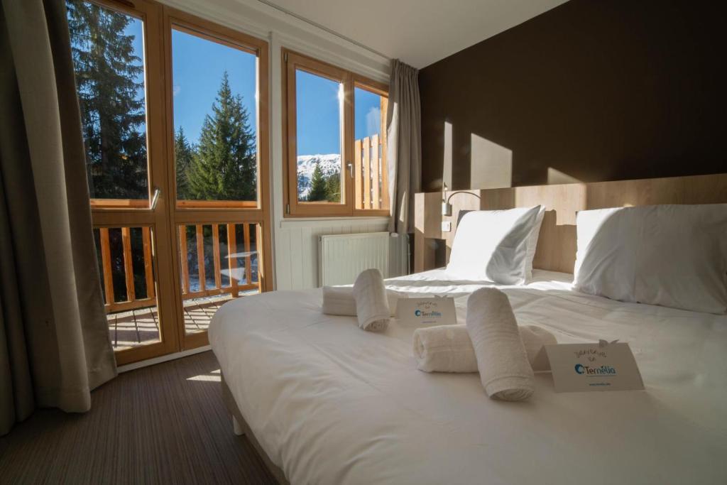 a bedroom with a large white bed with towels on it at Hôtel Le Chamois d'Or, USSIM Vacances Méribel in Méribel