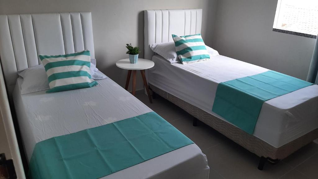 two twin beds in a room with a table at Apartamento encantador com estacionamento incluso em Tijucas in Tijucas