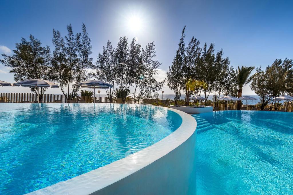 una gran piscina con agua azul y sombrillas en Barceló Lanzarote Royal Level en Costa Teguise
