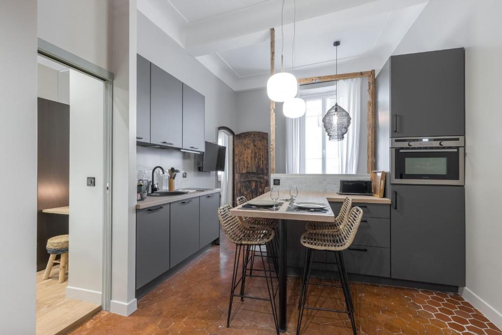 une cuisine avec des placards gris et une table avec des chaises dans l'établissement Charming 2 Bdr Old Town, à Nice