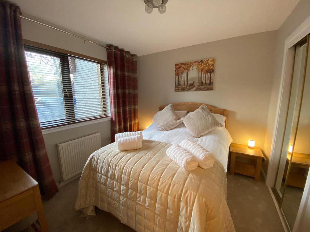 1 dormitorio con 1 cama con mantas y almohadas blancas en discoverNESS Apartment, en Inverness