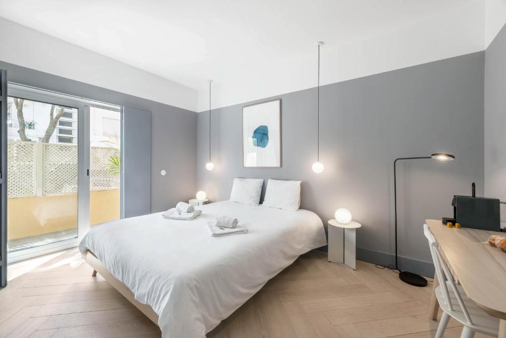 a bedroom with a large white bed and a window at Jardim Suites by Olala Homes in Cascais