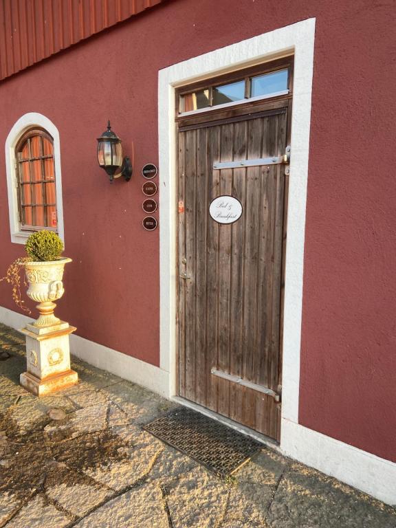 una puerta de madera de un edificio con un jarrón al lado en Bashults Gård en Jönköping