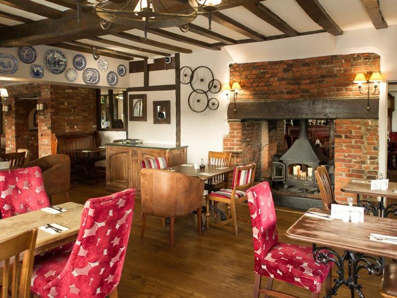 a dining room with a table and a fireplace at The White Horse Hotel and Luxury Shepherds Huts in Eye