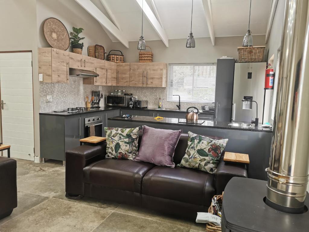 a living room with a leather couch in a kitchen at SiriMiri Cottage Dullstroom in Dullstroom