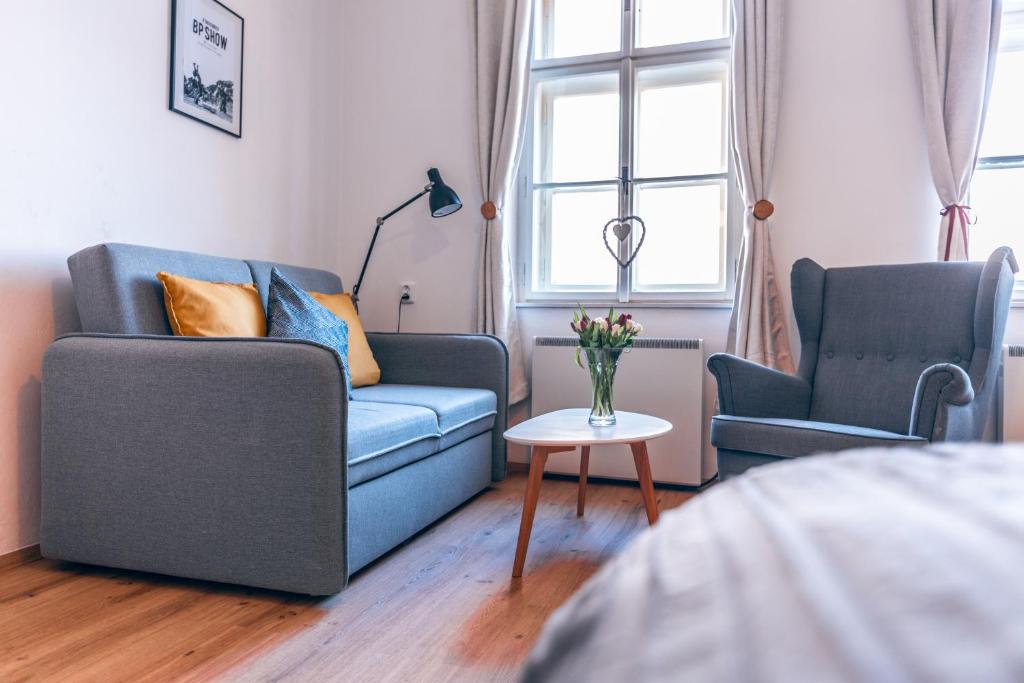 a living room with a blue couch and two chairs at Apartmány CAFÉ-CAFÉ in Jičín