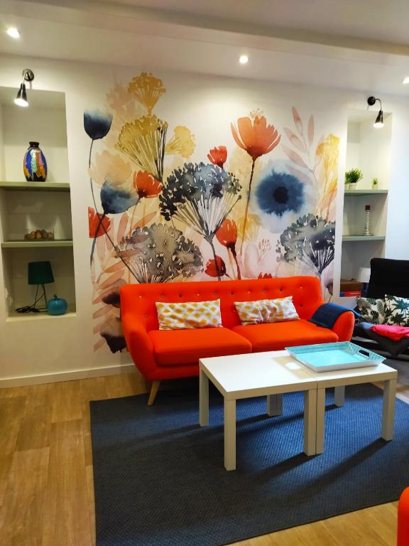 un salon avec un canapé orange et une fresque florale dans l'établissement Studio Top, à Perros-Guirec