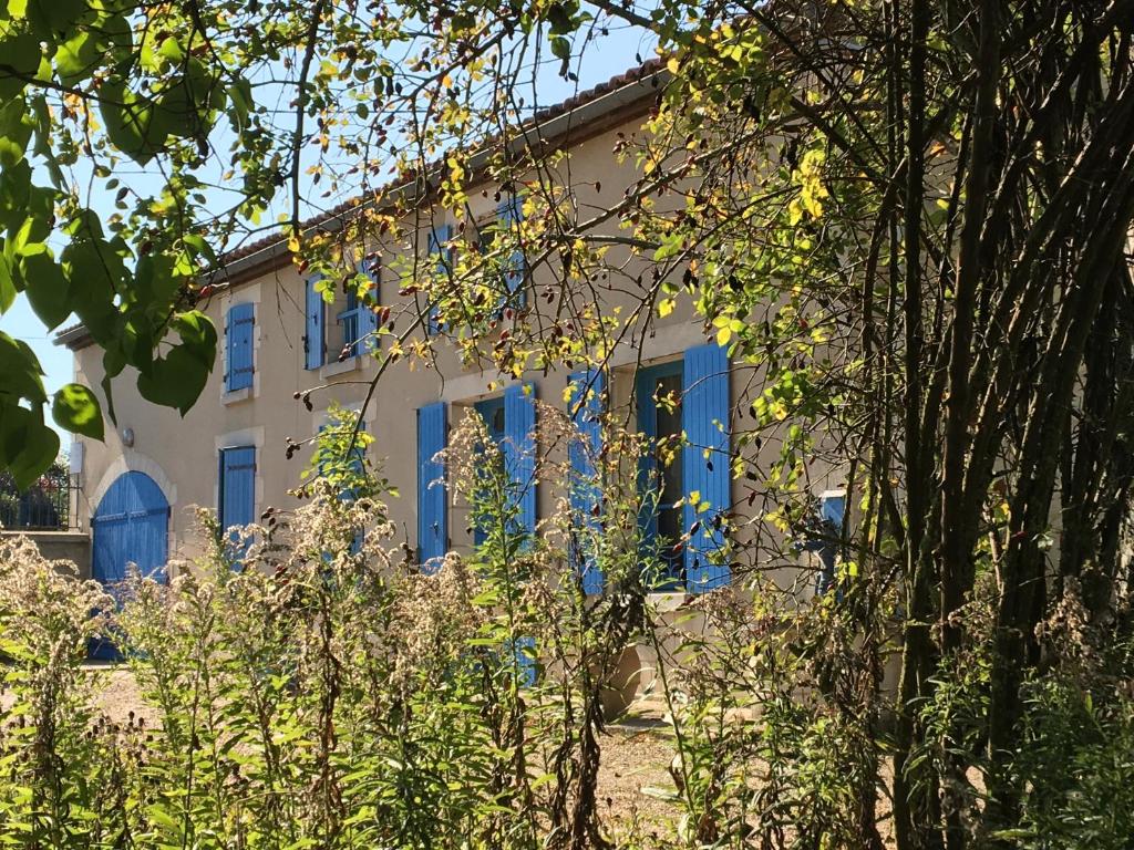 a white building with blue windows and trees at Maison d'hôtes La Chabanaise - Marais Poitevin in Cramchaban