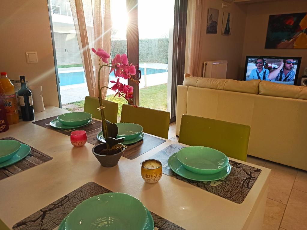una mesa de comedor con platos verdes. en Nikola's 4 season apartment by the sea and airport, en Porto Rafti