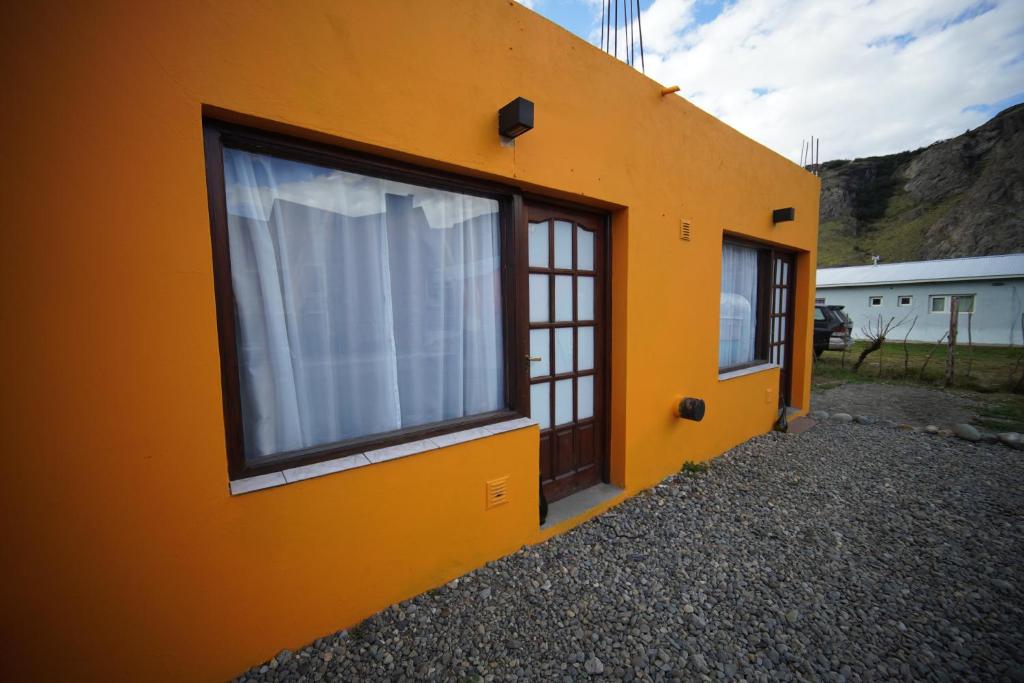 Un edificio naranja con una ventana con una cortina blanca. en Magna, en El Chaltén