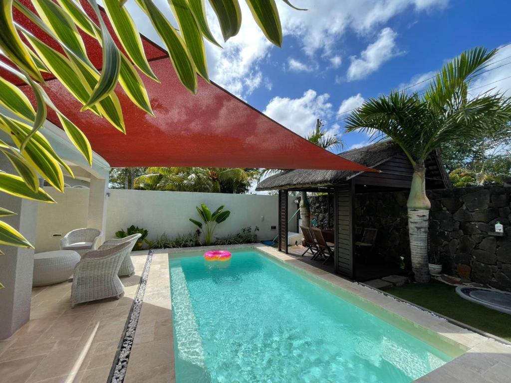 a swimming pool with a red umbrella over a house at HappInès Villa 3 bedroom Luxury Villa with private pool, near all amenities and beaches in Grand Baie