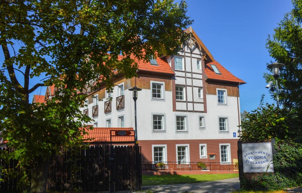 a large white building with a red roof at Vęgoria 17 Apartament przy porcie in Węgorzewo