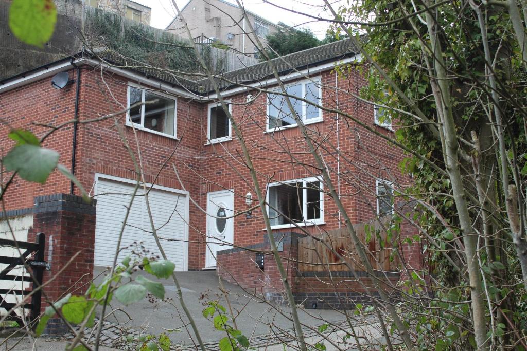 a red brick house with a white garage at 4 Bedroom Detached Holiday home with Hot Tub in Wrexham