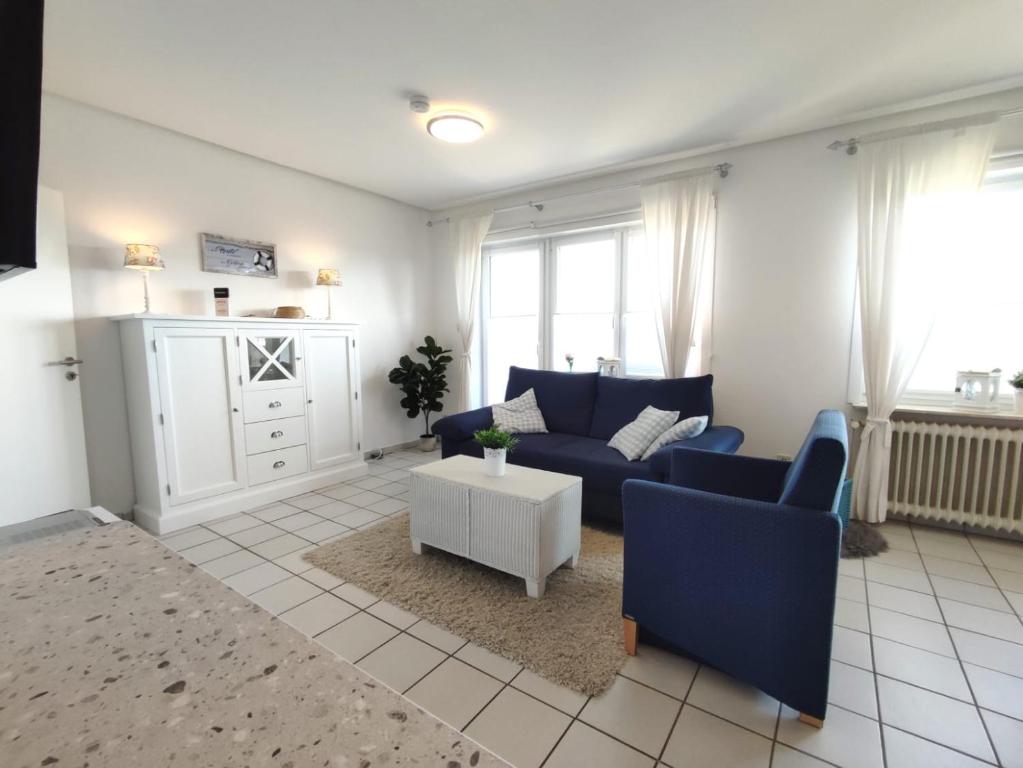 a living room with a blue couch and a table at Ferienwohnung am Deich in Friedrichskoog