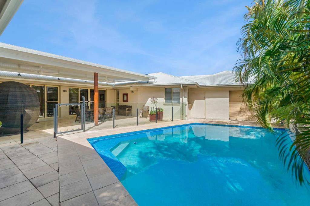 a swimming pool in front of a house at Frangipani Hideaway in Lennox Head