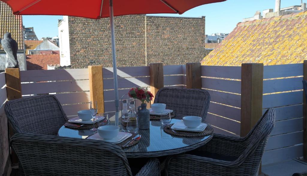 een tafel met stoelen en een parasol op een patio bij THE ROOFTOP - a trendy new apartment with airconditioning, large terrace & free parking in Oostende