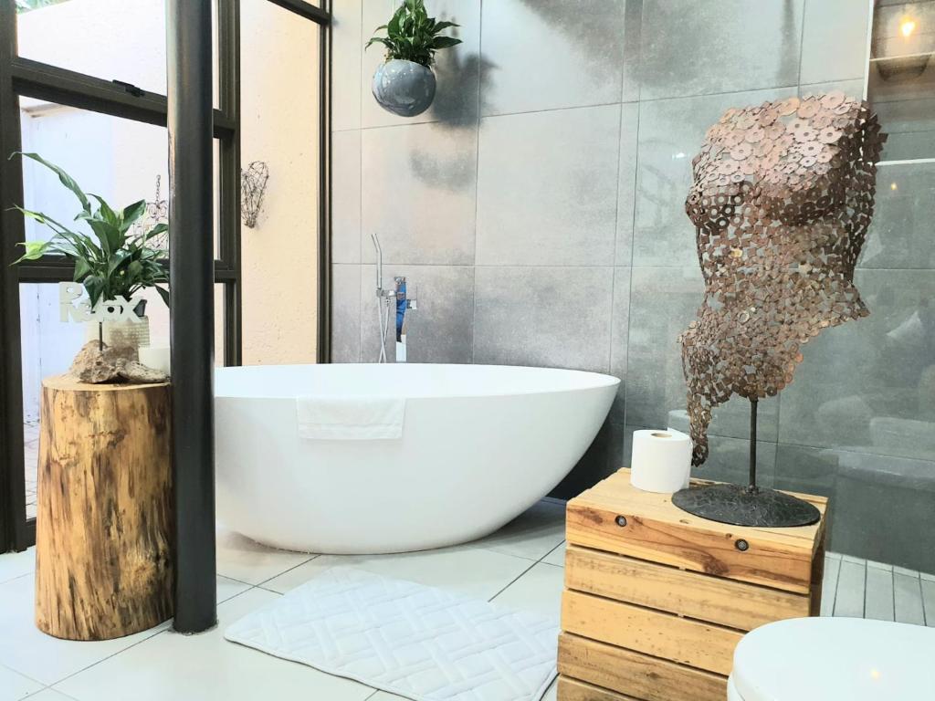 baño con bañera y una estatua de una cabeza en Bendor Garden Flat, en Polokwane