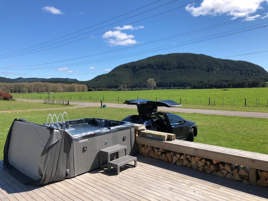 una bañera de hidromasaje en una terraza con un coche en un campo en Full holiday home to yourself, up to 21 guests en Atiamuri