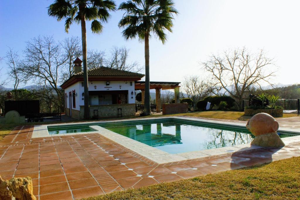 una piscina frente a una casa con palmeras en Casa LADI by CasaTuristica en Arriate