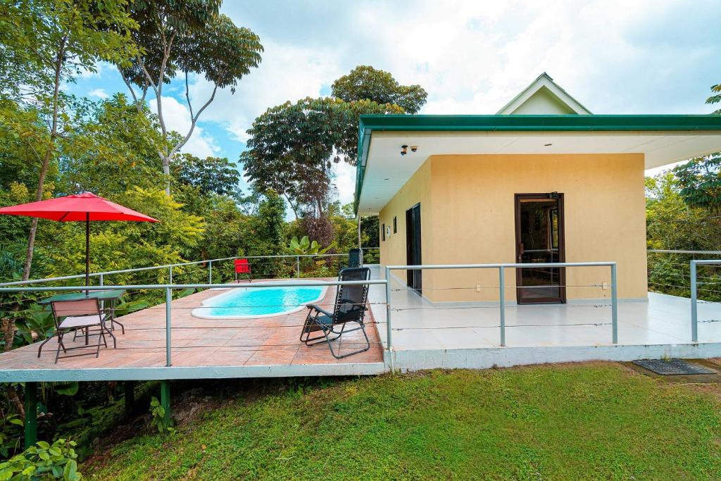 ein Haus mit einem Pool und einer Terrasse mit Stühlen und einem Sonnenschirm in der Unterkunft Toucan Villa Newer with WiFi & Pool - Digital Nomad Friendly in Manuel Antonio