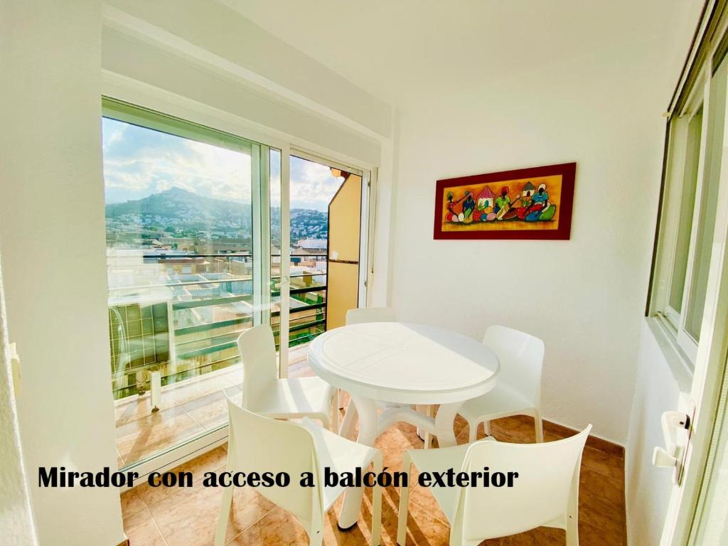 una mesa y sillas blancas en una habitación con ventana en Labradores 3 dormitorios, en Peñíscola