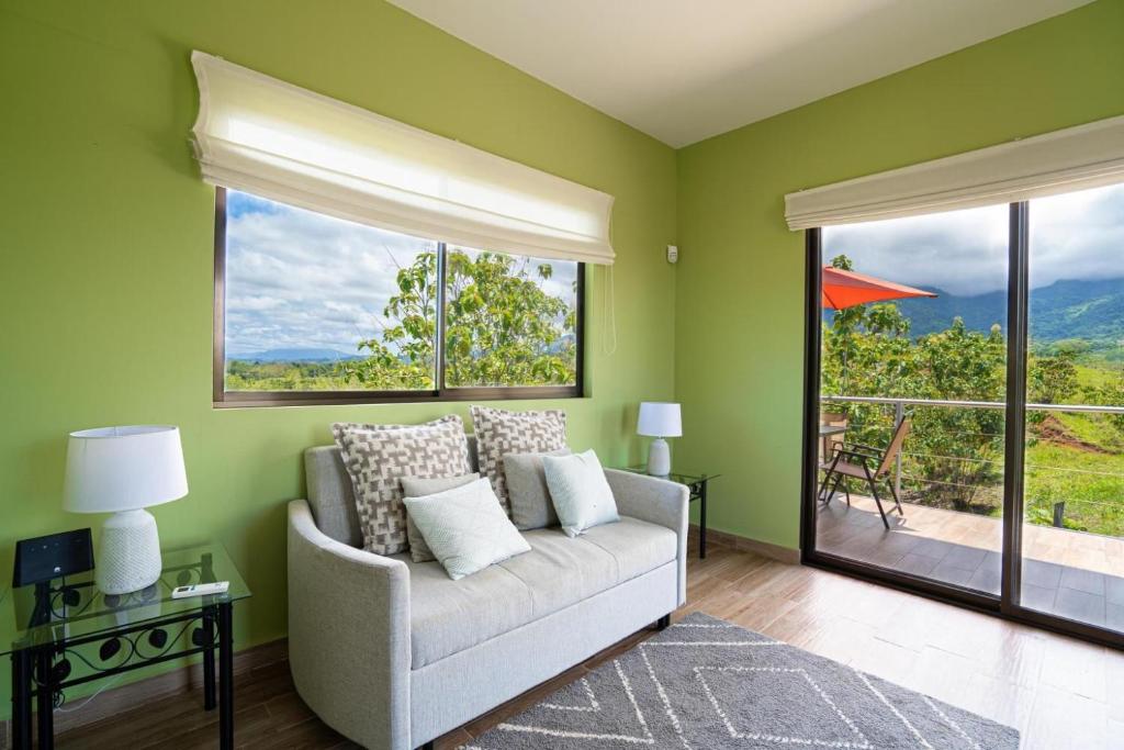 a living room with a couch and large windows at Villa Kiskadee - Beautiful Mountain Views with Private Pool & Wi-Fi in Quepos