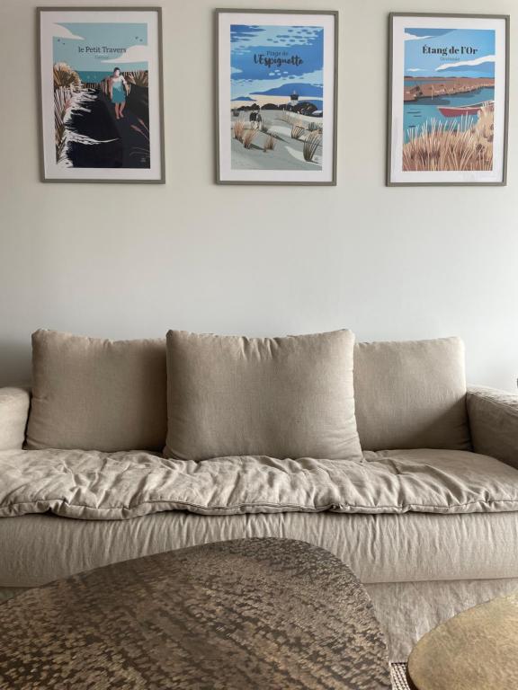 un sofá en una sala de estar con tres cuadros en la pared en Le P'tit Carnon en Mauguio