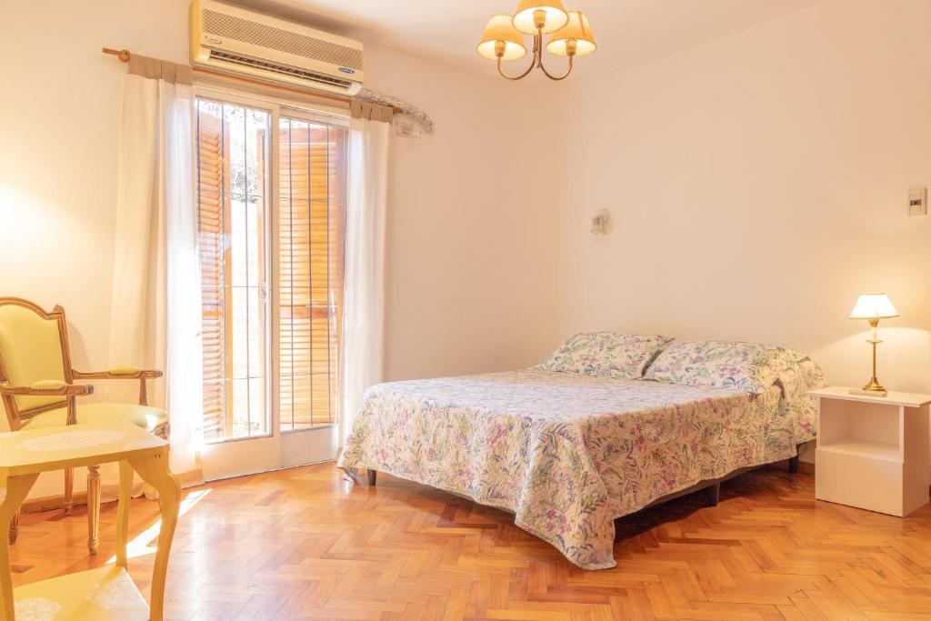 een slaapkamer met een bed, een stoel en een raam bij Hostel Boutique PASO in Mendoza