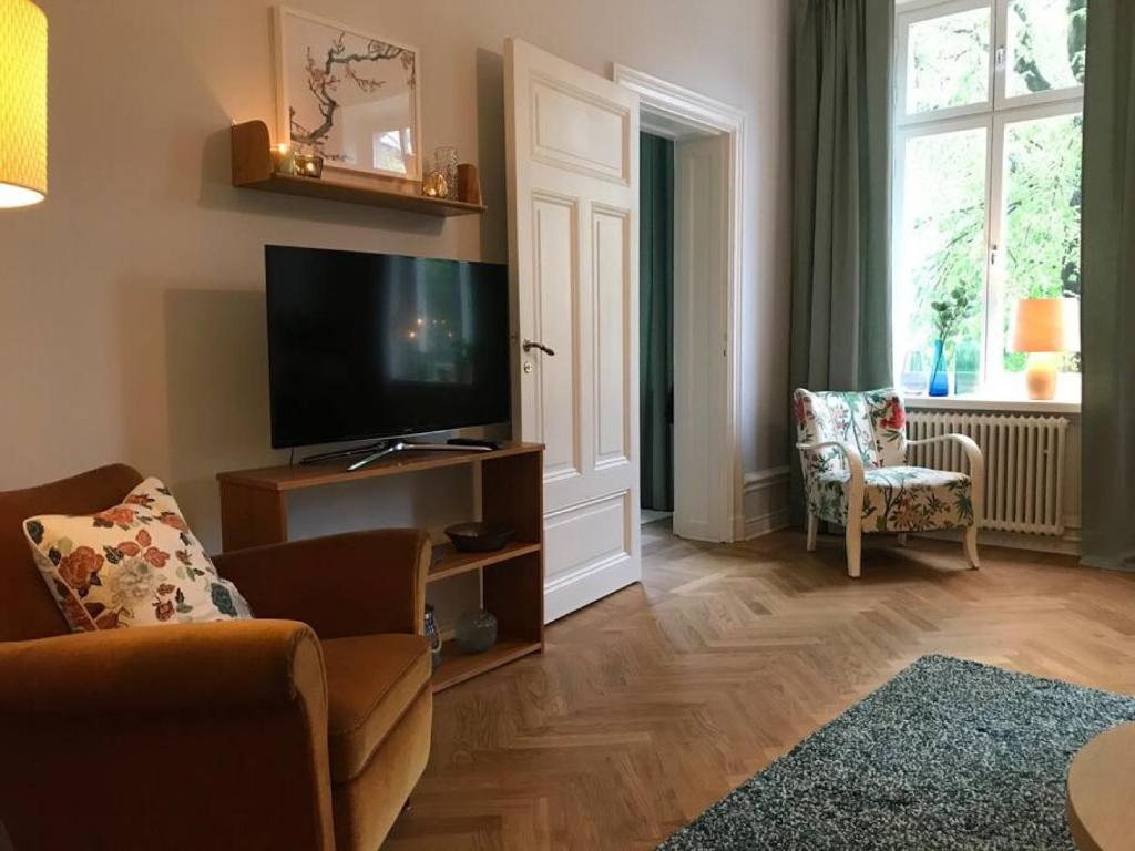 Il comprend un salon doté d'une télévision à écran plat et d'un canapé. dans l'établissement Artistic and light 2 room apartment in SoFo 65sqm, à Stockholm