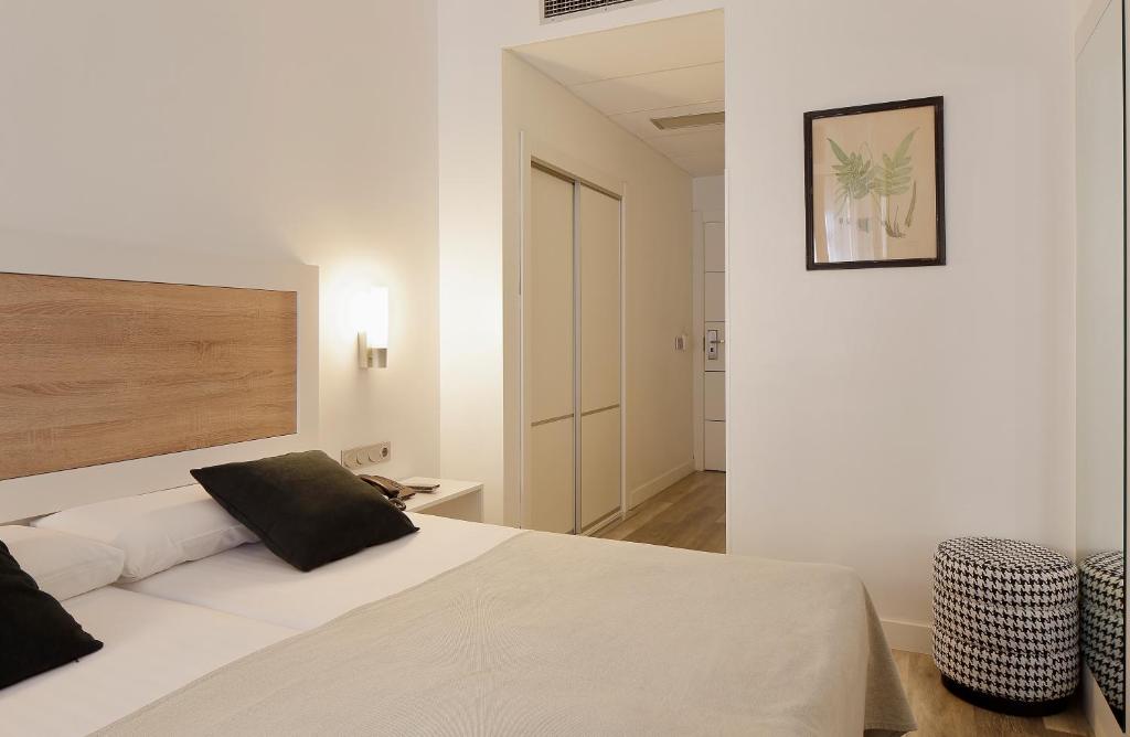 a bedroom with a large white bed and a chair at Hotel Santa Rosa, Blue Hoteles in Gijón