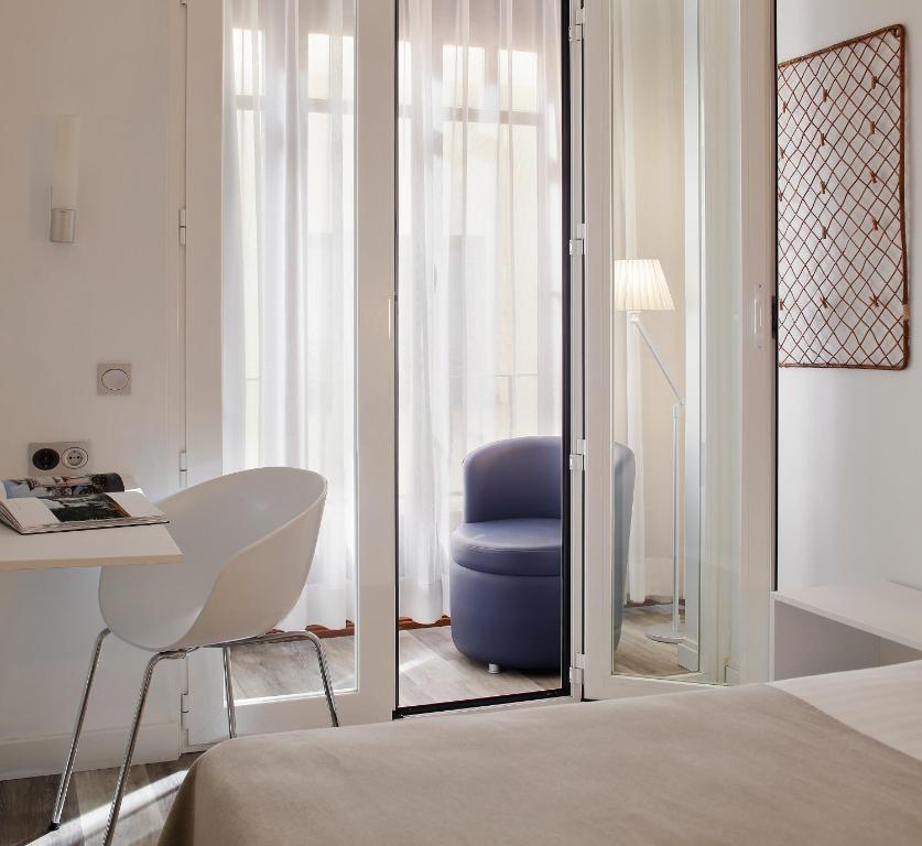 a bedroom with a blue chair and a desk at Hotel Santa Rosa, Blue Hoteles in Gijón