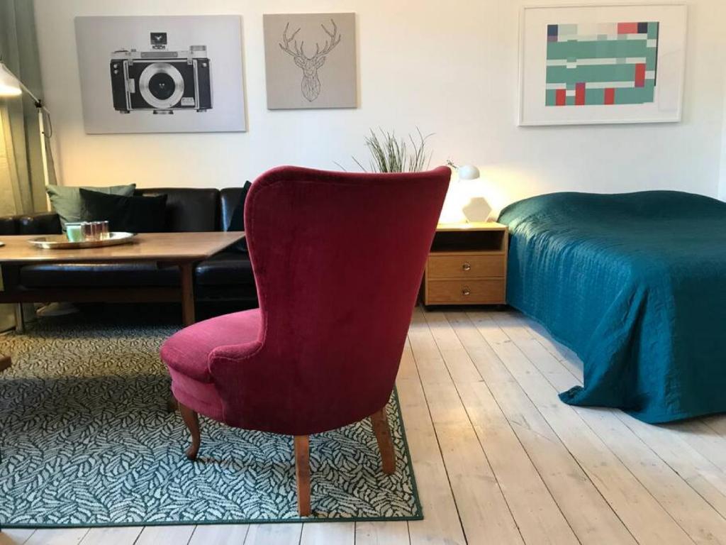 a living room with a red chair and a bed at Bohemian and light one room apartment in SoFo 31sqm in Stockholm