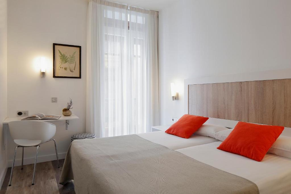 a bedroom with a large bed with orange pillows at Hotel Santa Rosa, Blue Hoteles in Gijón