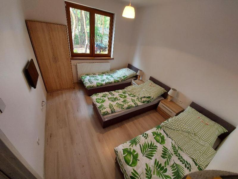 a room with three beds and a window at Apartament Nad Jeziorem Brenno in Brenno