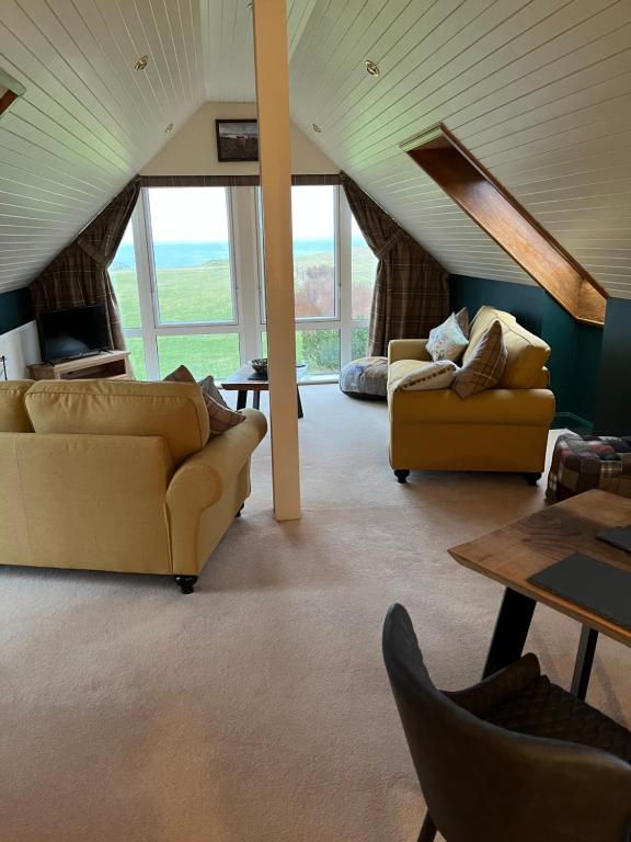 a living room with two couches and a table at Pentland view croft with a sea view in Melvich